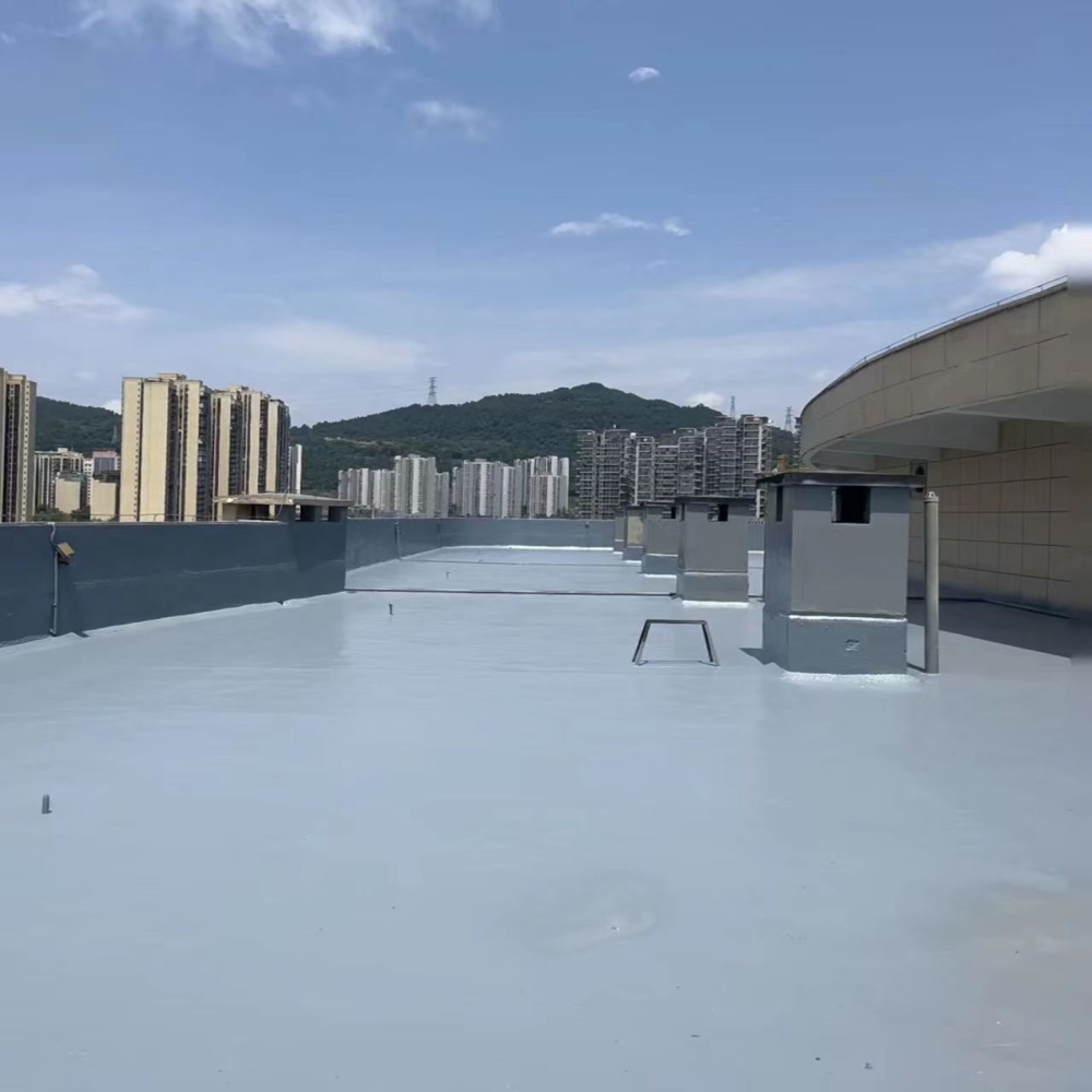 A wide, flat rooftop covered with a smooth, light-gray polyurea waterproof coating, featuring ventilation units and parapet walls, with urban high-rises and green hills visible in the background