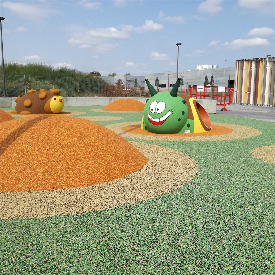 A vibrant outdoor children’s playground featuring colorful EPDM rubber granule flooring in green, orange, and beige, with whimsical animal-shaped play structures — including a smiling green ca