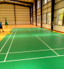 Indoor badminton court with green Silicon PU flooring, showing slip resistance & elasticity for pro sports.